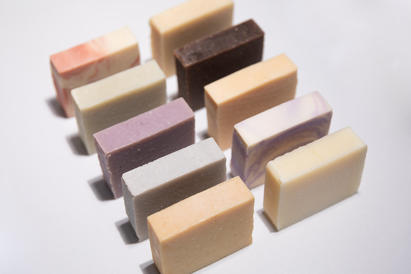 Two rows of soap bars lined up on a white surface
