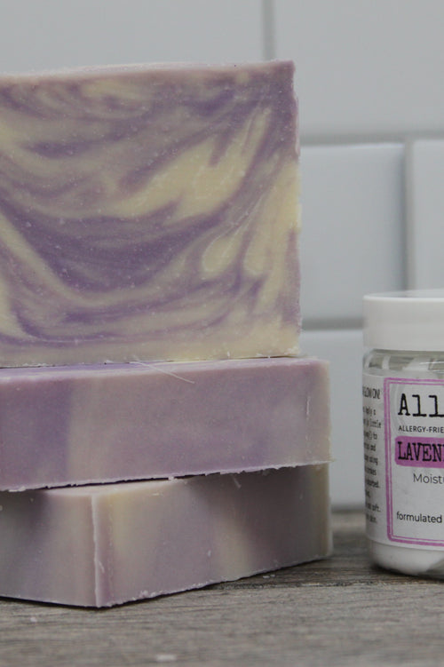 three bars of purple and white swirl lavender chamomile soap next to lavender chamomile lotion